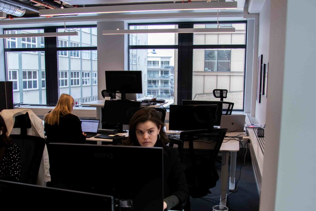 Två anställda från Ants sitter vid sina kontorsplatser och jobbar med rekrytering på sina datorer.