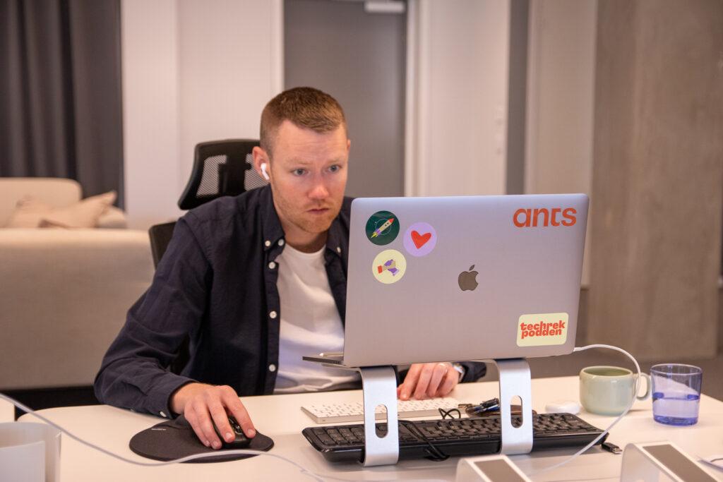 En person från Ants arbetar vid sin dator för att skriva en artikel om att rekrytera inom IT-säkerhet. 