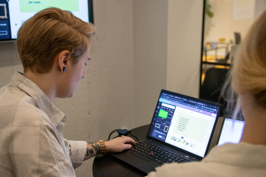 En person arbetar bredvid sin kollega vid sin dator med att rekrytera ingenjörer.
