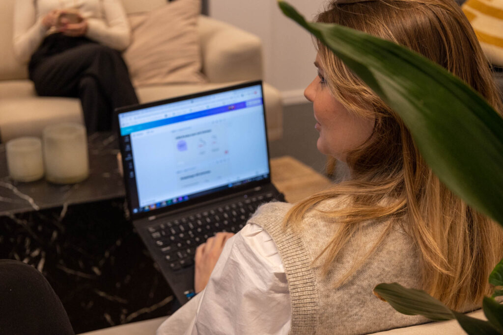 En person sitter i en soffa med en laptop i knäet och pratar med någon utanför bild om att rekrytera SOC analyst.