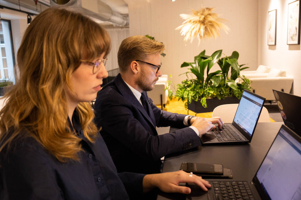 Två personer sitter tillsammans och arbetar på sina laptops