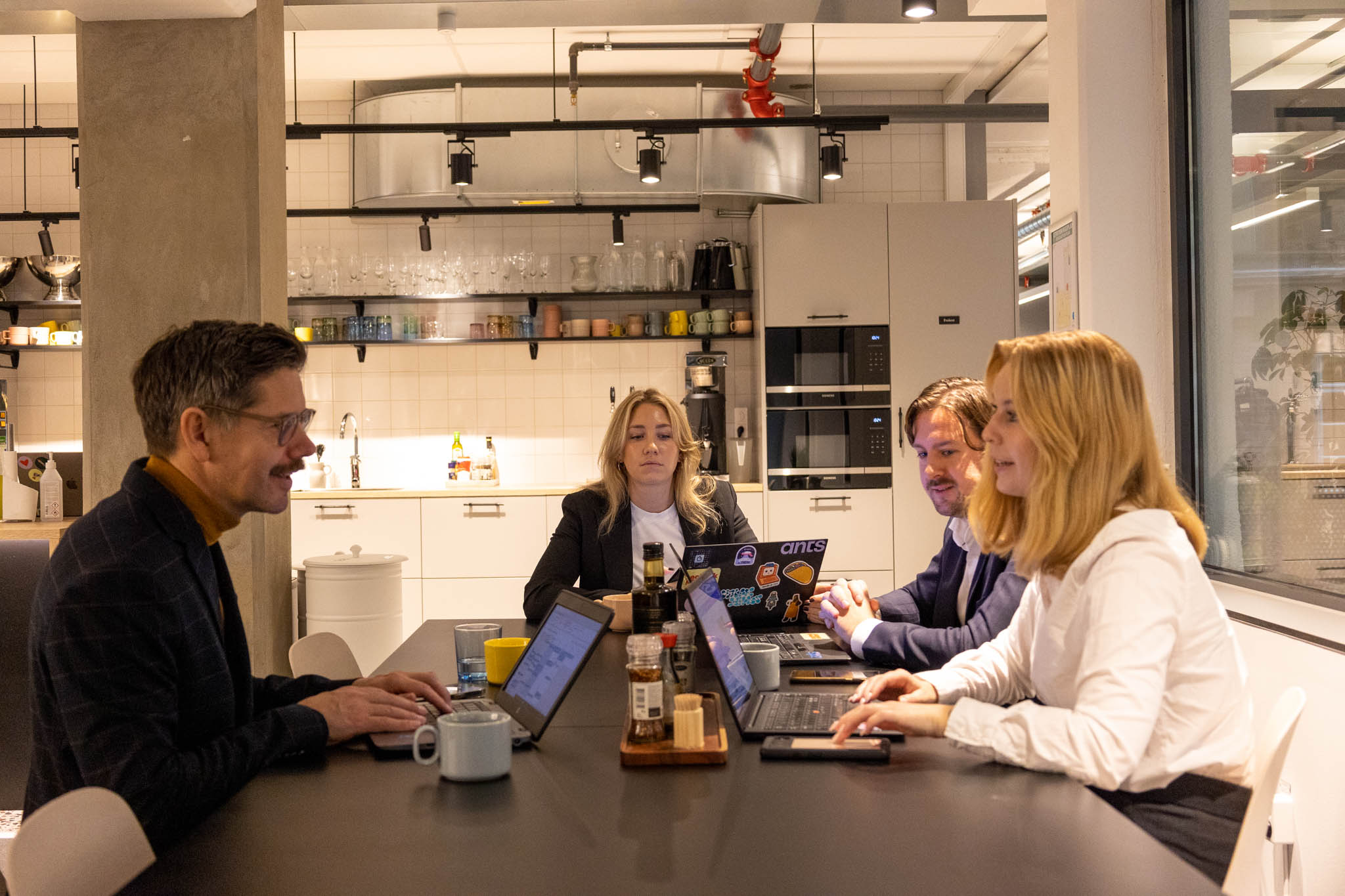 Personer sitter vid ett bord framför laptops och pratar om marknadsföring rekrytering.