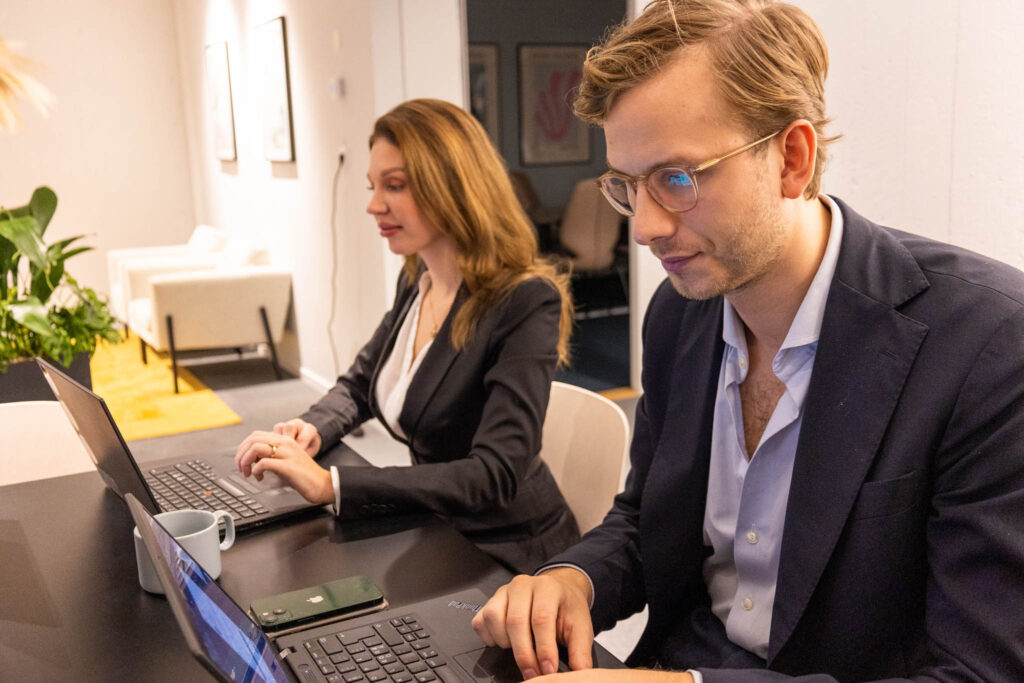 Två personer sitter vid ett bord framför laptops och läser om marknadsföring rekrytering.