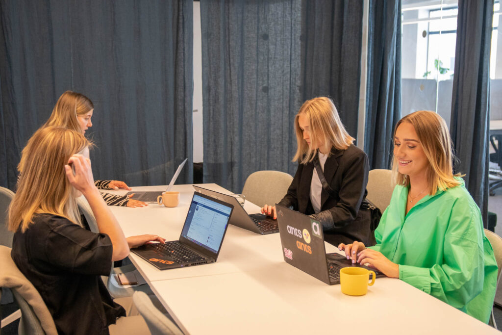 Personer sitter vid ett bord framför laptops och läser om att rekrytera Marketing Automation Manager.