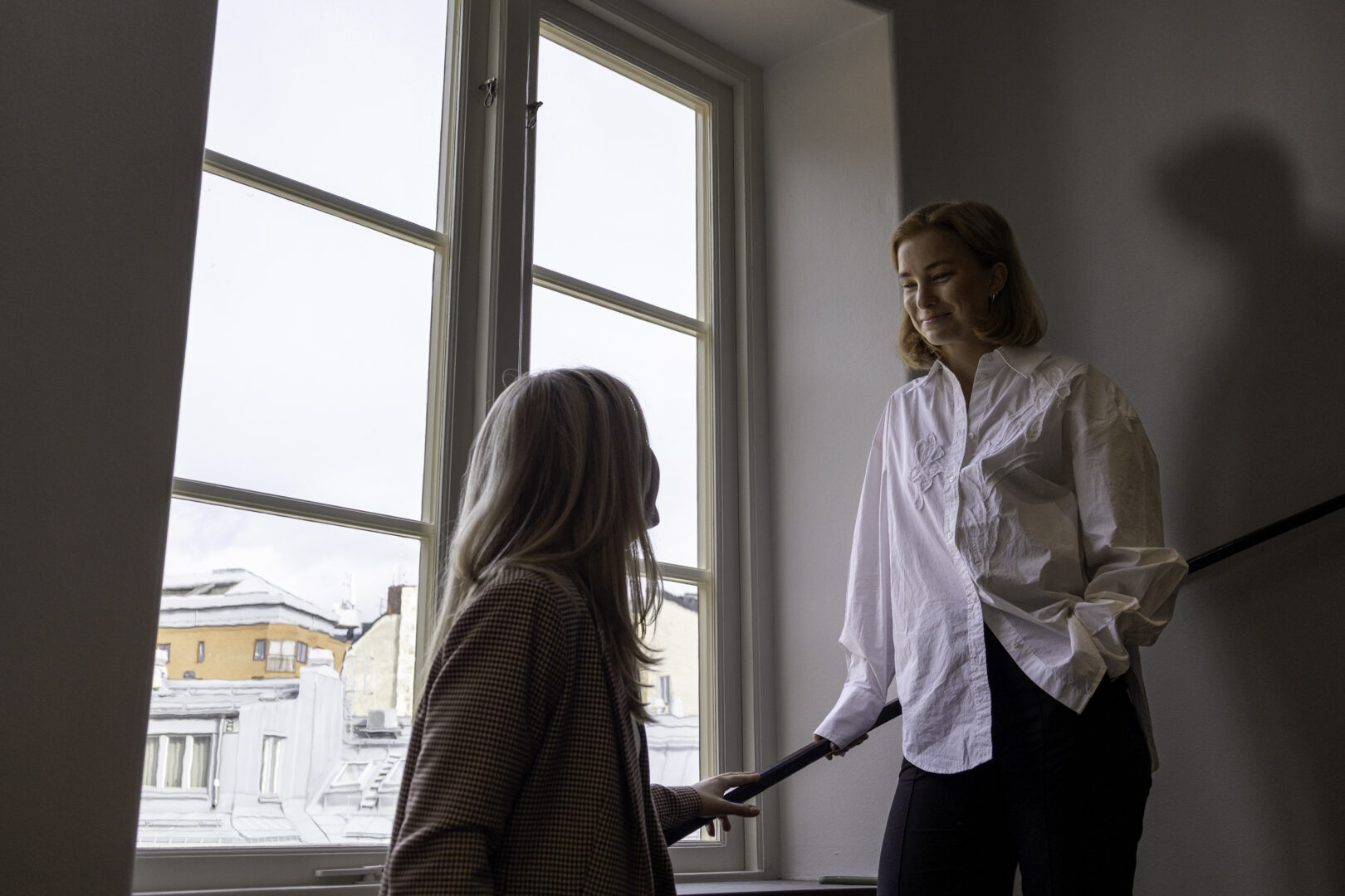 Två IT-rekryterare som står och samtalar om Skills-based hiring vs. erfarenhetsbaserad rekrytering i ett trapphus